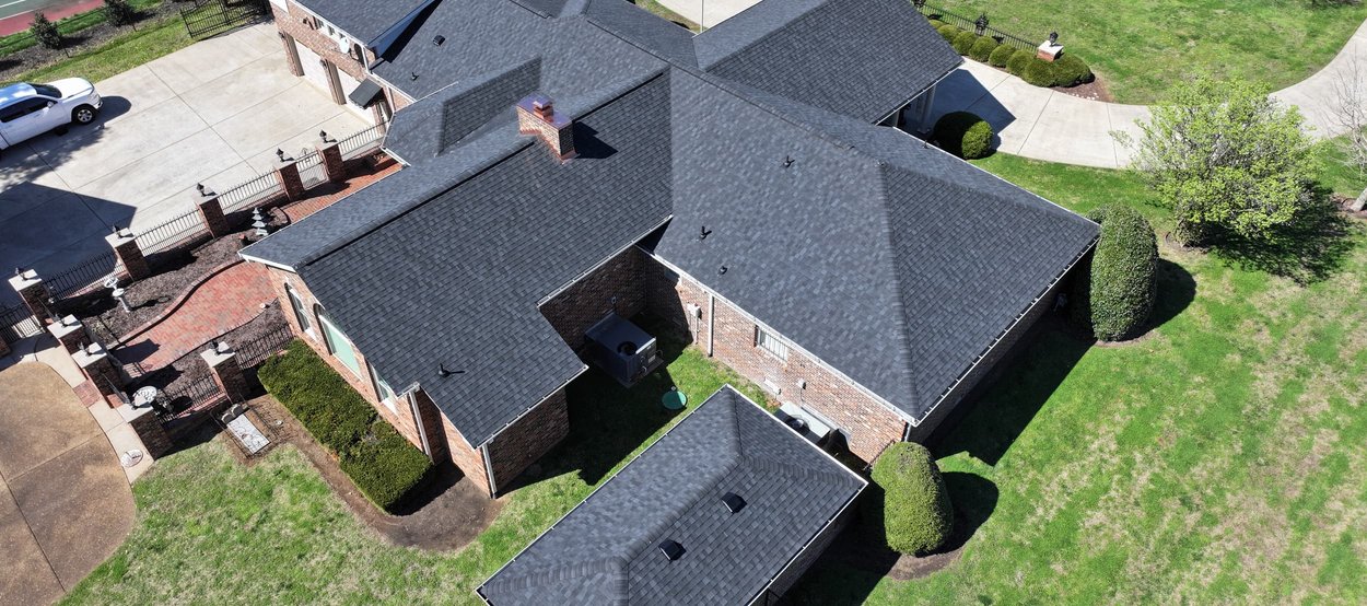 A modern home with a well-maintained asphalt shingle roof, featuring clean lines, proper gutter systems, and contrasting trim.
