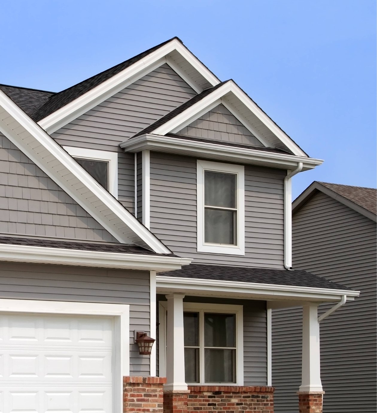 A modern home with a well-maintained asphalt shingle roof, featuring clean lines, proper gutter systems, and contrasting trim.
