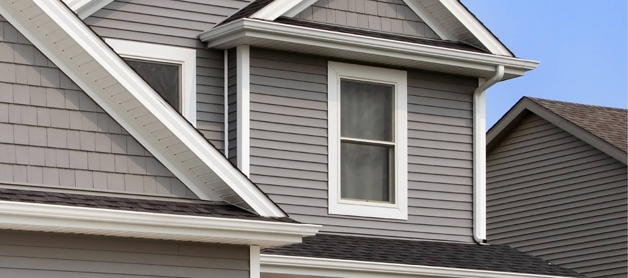 A modern home with a well-maintained asphalt shingle roof, featuring clean lines, proper gutter systems, and contrasting trim.