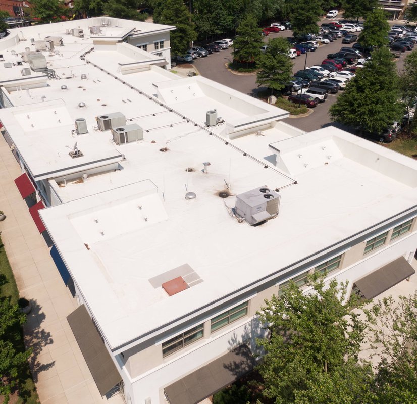 A commercial building with a large, flat, white roof, complete with various HVAC units.