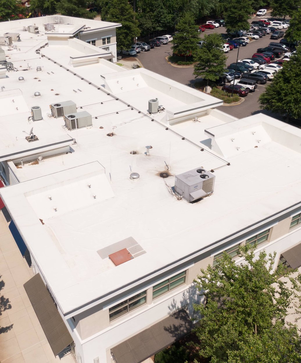 A commercial building with a large, flat, professionally maintained roof featuring HVAC units and proper drainage systems.