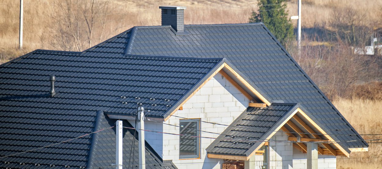 A new house under construction with a modern, dark-colored tile roof.