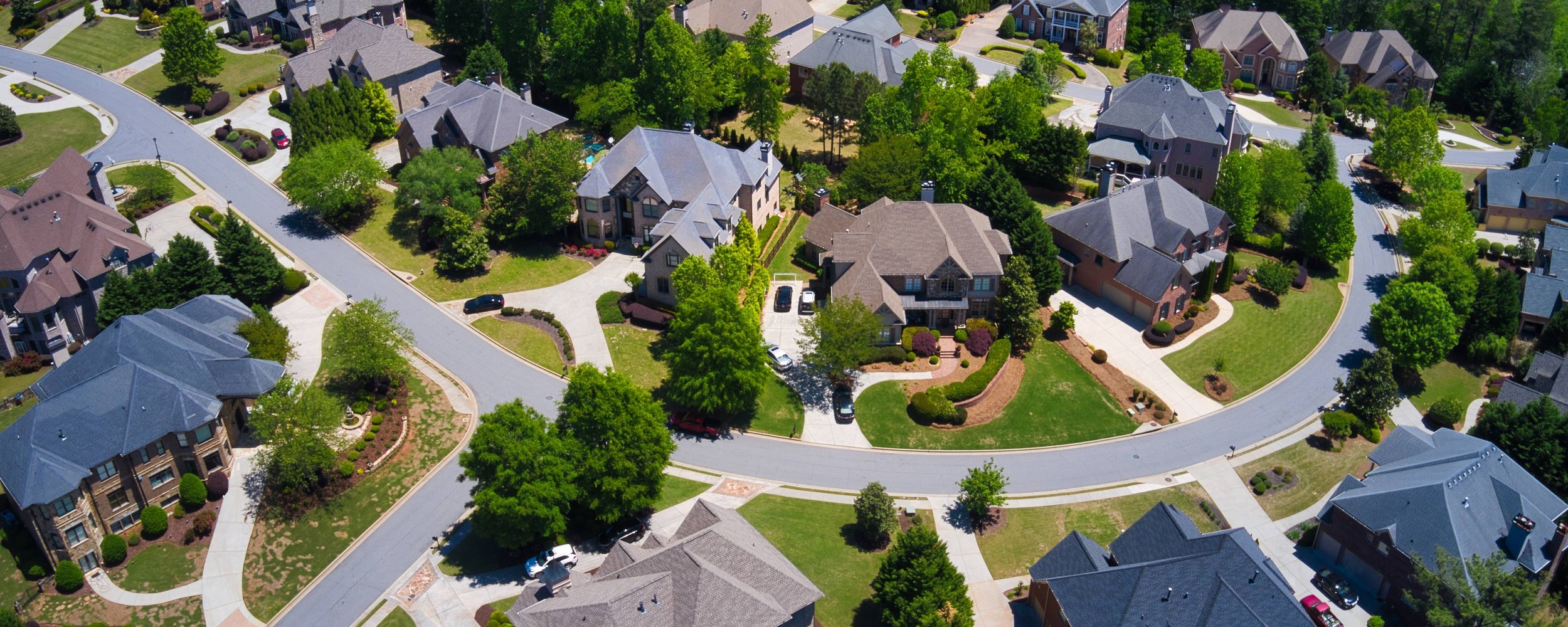 Aerial view showcasing a well-maintained residential neighborhood with a variety of roof styles and conditions.