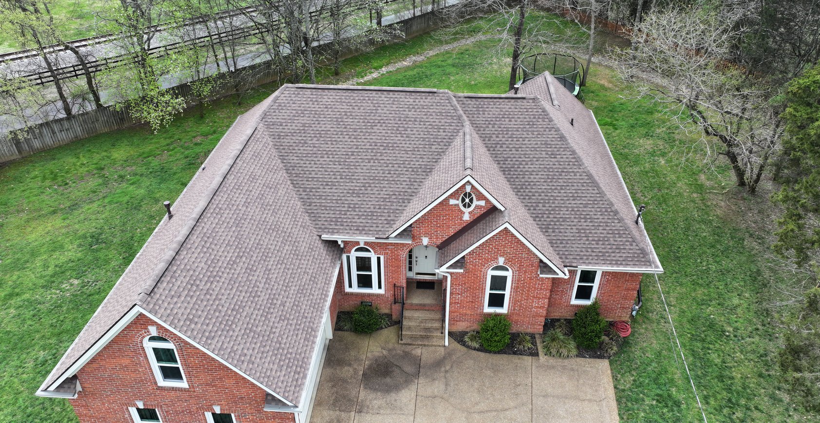 A residential building with a damaged roof covered by a large blue tarp.